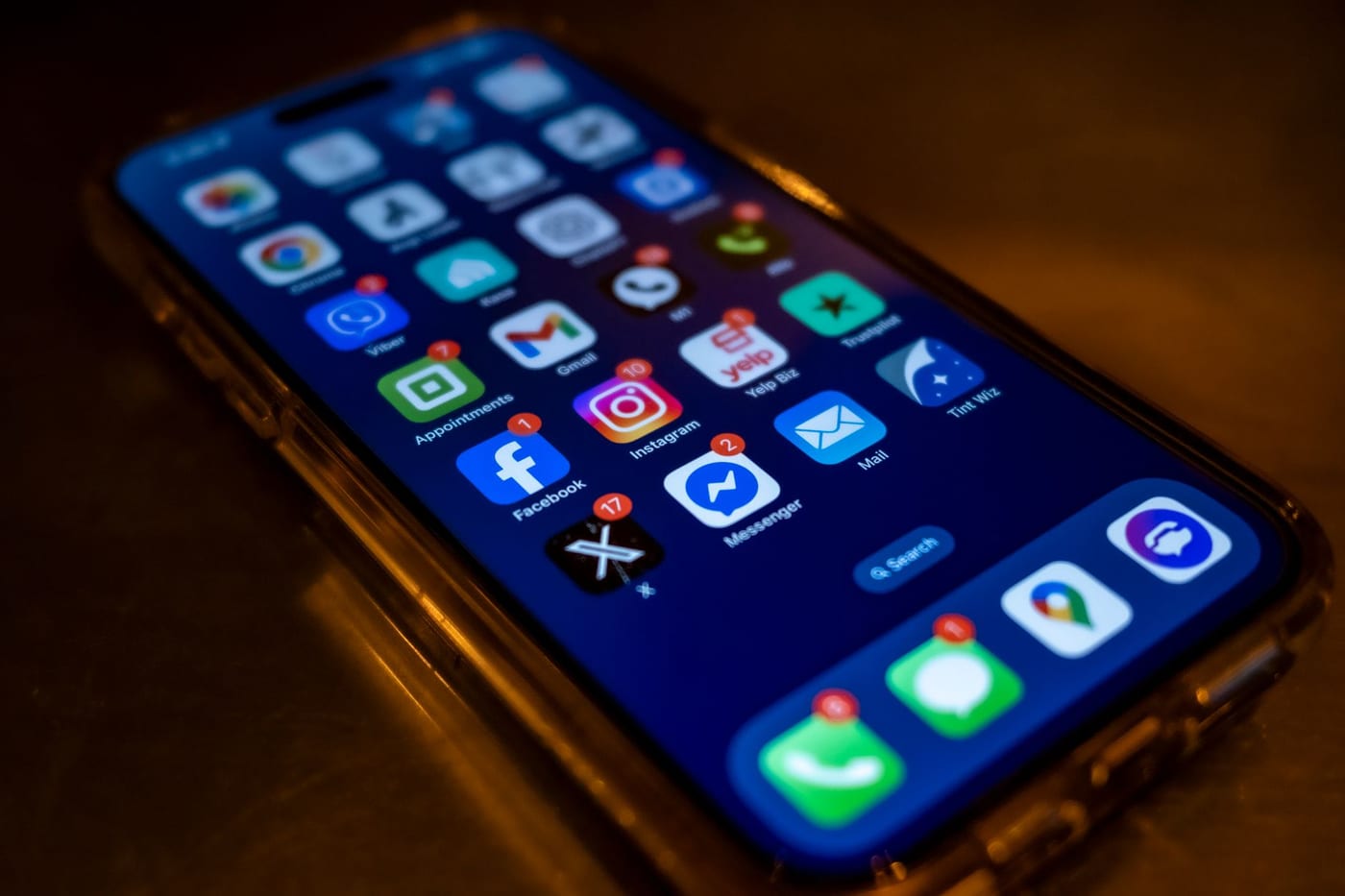 A smartphone lying on a desk, its screen filled with app icons carrying unread notification badges.